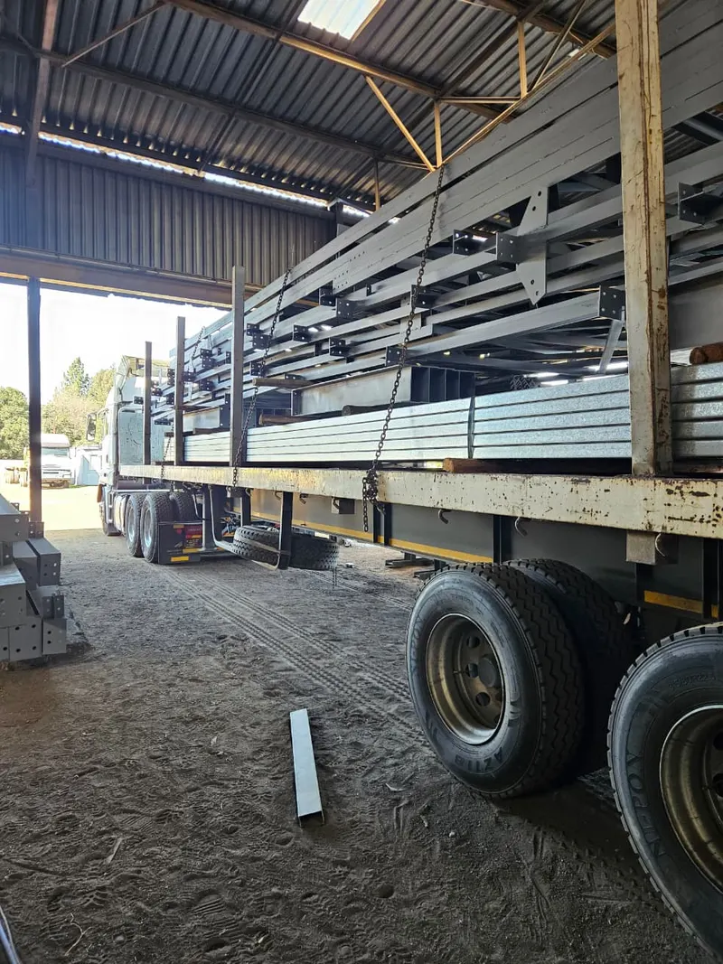 SteelBand Projects flatdeck trailer loaded with structural steel roofing sheets in a warehouse